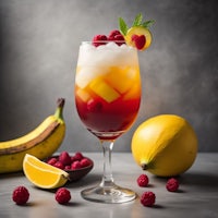 a drink with raspberries and bananas on a gray background